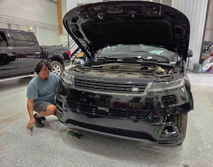 auto body technician taking off a Land Rover bumper repair at Heritage Collision auto-body-technician-taking-off-a-Land-Rover-bumper-repair-at-Heritage-Collision
